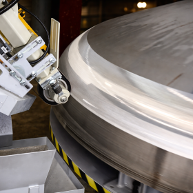 Gros plan sur une machine FARROS de meulage de fonds de la gamme H FARROS, machine-outil de meulage industriel avec tête flottante de meulage et tête de meulage industrielle travaillant l’extérieur d’un fond de cuve inox grande dimension, pour le meulage de fonds bombés, elliptiques ou hémisphériques, le traitement des fonds de cuves, la reprise de soudures, le meulage de pièces courbes et de formes complexes, avec finition homogène des surfaces en chaudronnerie et tôlerie.